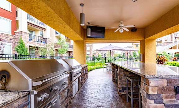 A patio with a stone wall and a grill.