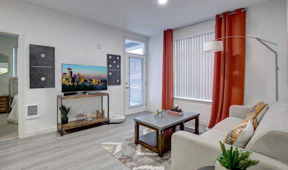 A living room with a grey couch, a coffee table, and a painting of a city skyline on the wall.