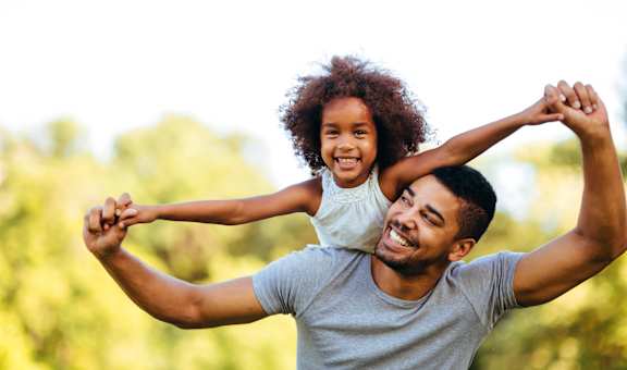 A man is lifting a little girl in the air.
