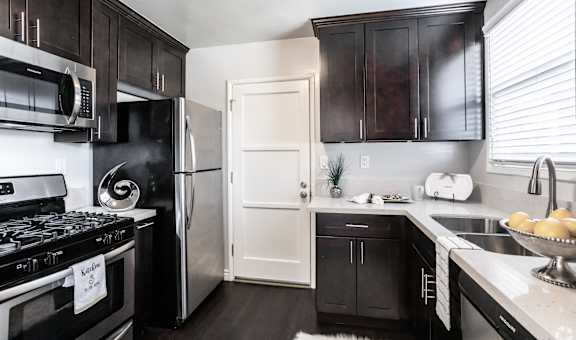A kitchen with black cabinets and a white door.