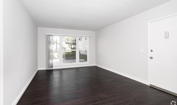 A room with a white door and a window with a view of the outside.