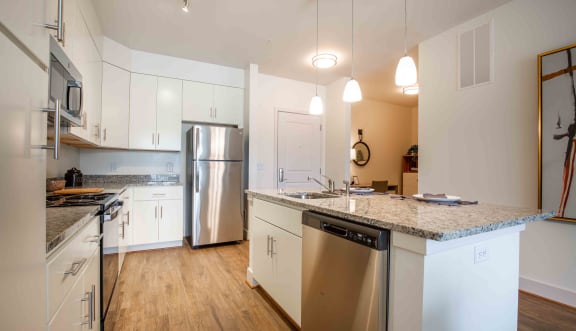 A kitchen with white cabinets and stainless steel appliances at Woodmore Grand Apartments in Bowie, MD