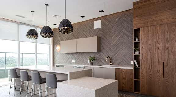 A modern kitchen with a white island and grey chairs.