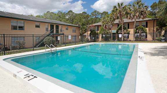 A swimming pool in a residential area with apartment buildings in the background.