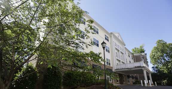 A white building with a tree in front of it.