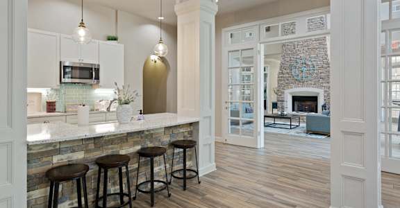 A kitchen with a bar area and a fireplace in the living room.