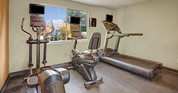 A home gym with a treadmill, elliptical trainer, and other exercise equipment.