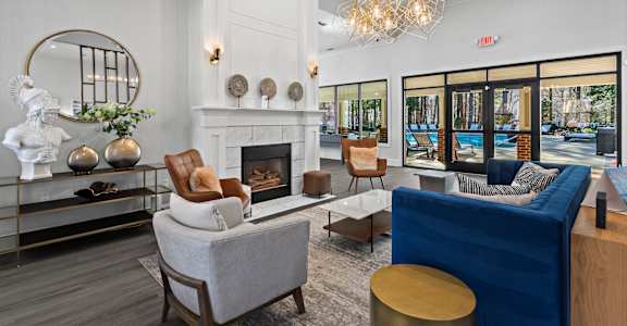 A living room with a fireplace, a blue couch, and a round mirror.
