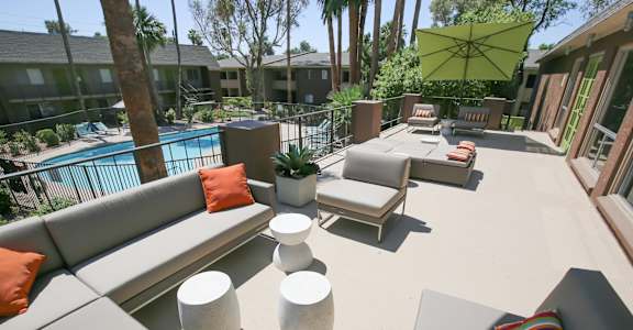 a large patio with couches and tables and a pool
