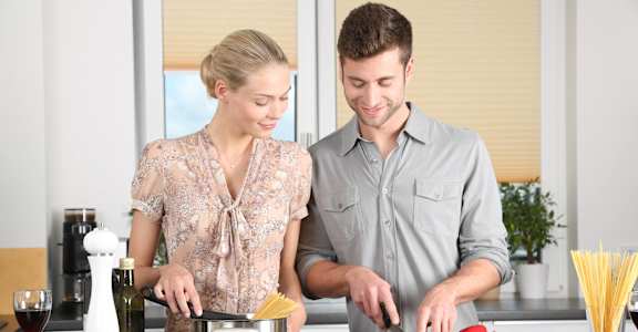 A man and woman are cooking together in a kitchen.