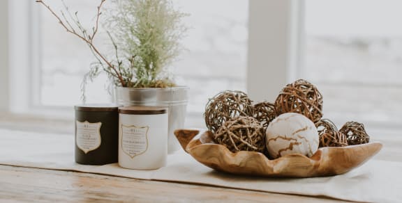 Candle and trinkets on wooden table by window