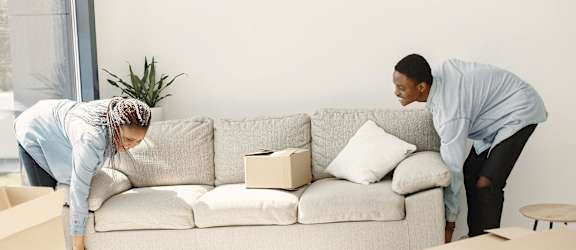 Two people unpacking boxes in a living room.