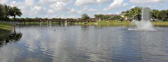 A fountain in the middle of a lake with a cloudy sky above.