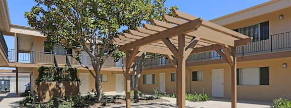 a courtyard with awning and trees in front of a building