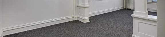 A room with white walls and a grey carpet.