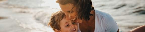 a mother holding her son on the beach