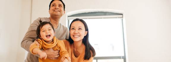 A family of three is standing in a room.