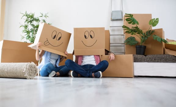two people sitting on the floor holding boxes with smileys on their faces