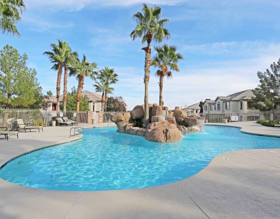 a pool with a rock waterfall and palm trees in the background at Carlisle at Summerlin Apartments ,Las Vegas, Nevada, 89144