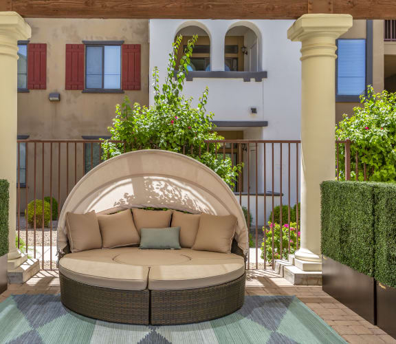 a patio with a couch and a rug in front of a building