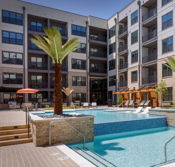 a swimming pool with palm trees in front of an apartment building