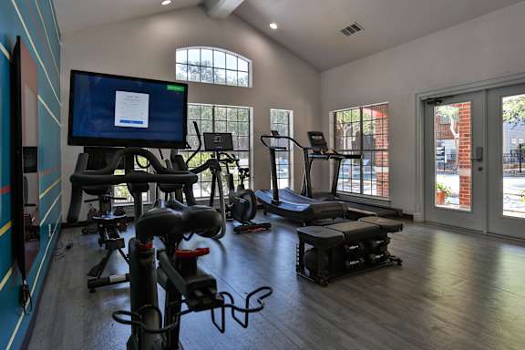 A gym with exercise equipment and a television displaying a webpage. at The Quarry Alamo Heights Apartments, Texas, 78209