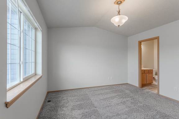A room with a grey carpet and a wooden door.