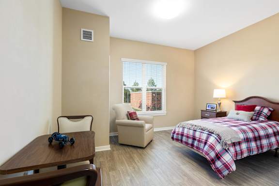 a bedroom with a bed and a chair and a table