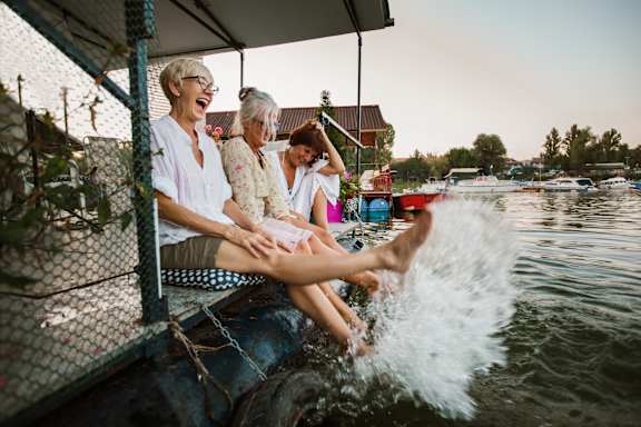 Three people are sitting on a boat, laughing and enjoying the ride.