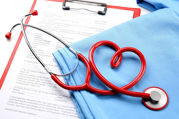 A doctor in a white coat is writing on a clipboard.