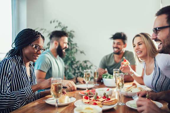 a group of people sitting around a table eating food and drinking wine