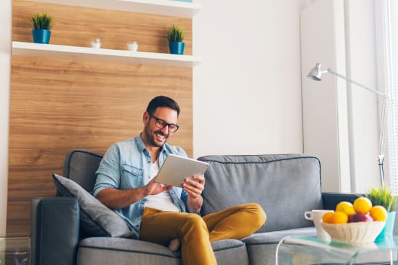 a man sitting on a couch using a tablet