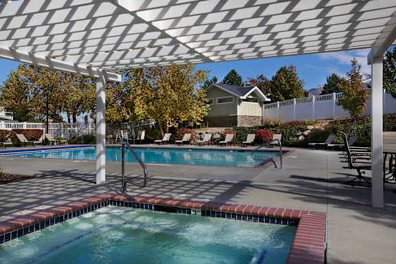 A pool under a white canopy with trees in the background.