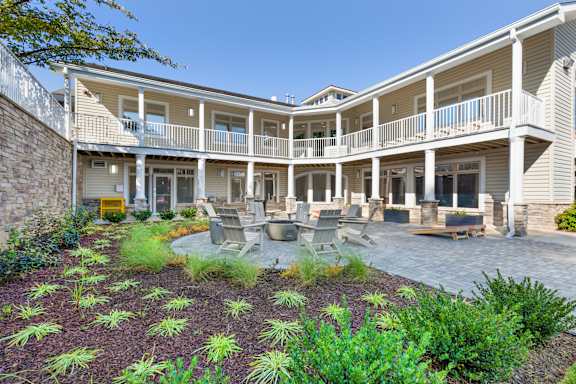 A courtyard with a stone wall and a grassy area with plants at Copper and Quarry Village, Pikesville, MD
