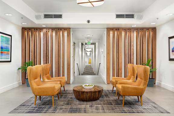 A hallway with a row of chairs and a coffee table.