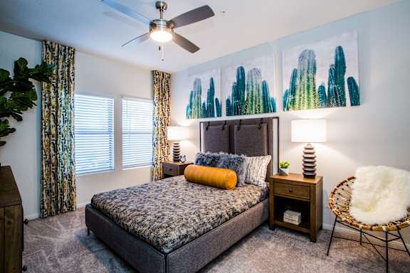 A bedroom with a bed, a chair, and a ceiling fan.