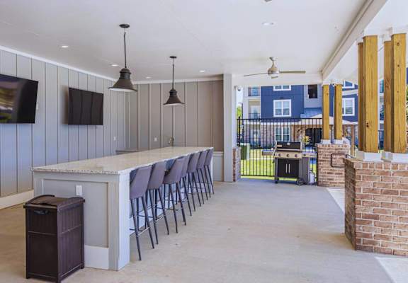 a long bar with chairs in a room with a grill