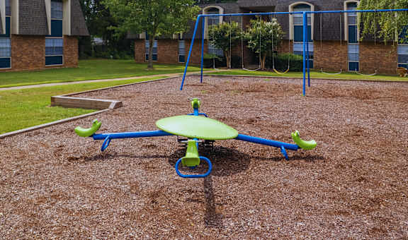 a playground with a swing set in front of a building