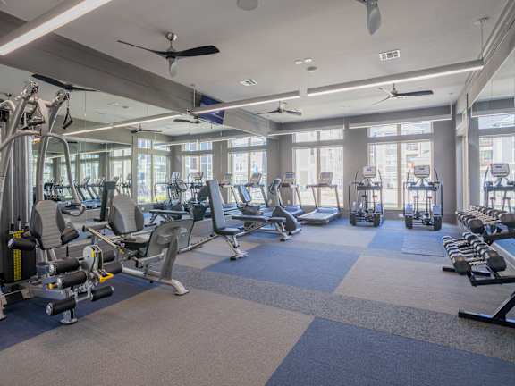a gym with cardio equipment and windows in a building