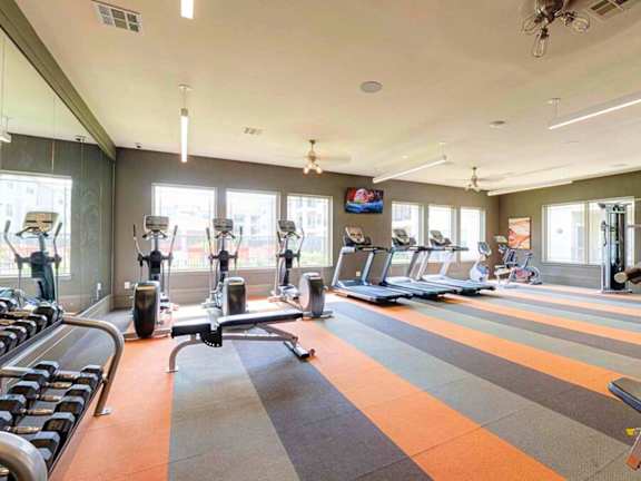 a gym with cardio equipment and windows