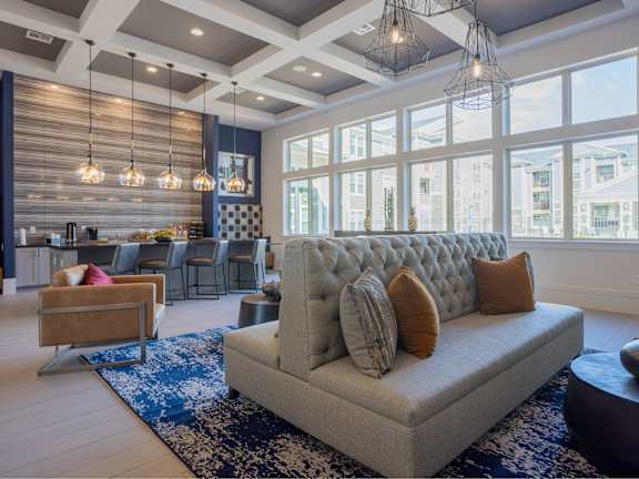 a living room with a couch and chairs in front of large windows
