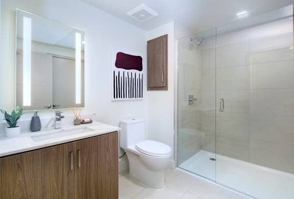 A modern bathroom with a toilet, sink, and glass shower.
