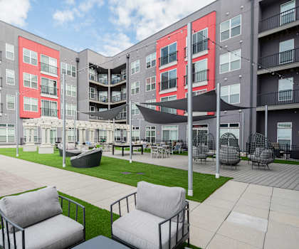 an outdoor area with chairs and a lawn in front of an apartment building