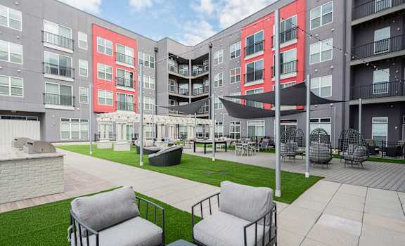 an outdoor area with chairs and a lawn in front of an apartment building