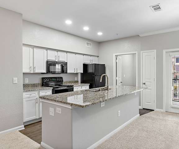 an open kitchen with granite counter tops and white cabinets at The Vista on Brodie, Austin, Texas