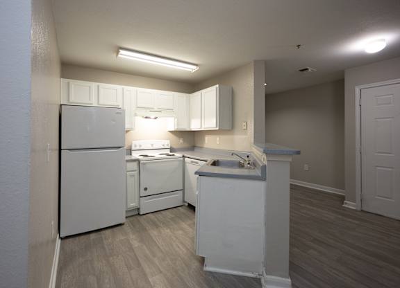 an empty kitchen with white appliances and white cabinets at Magnolia Pointe Apartments in Duluth, GA