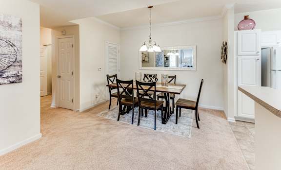 a dining room with a table and chairs and a kitchen with a refrigerator