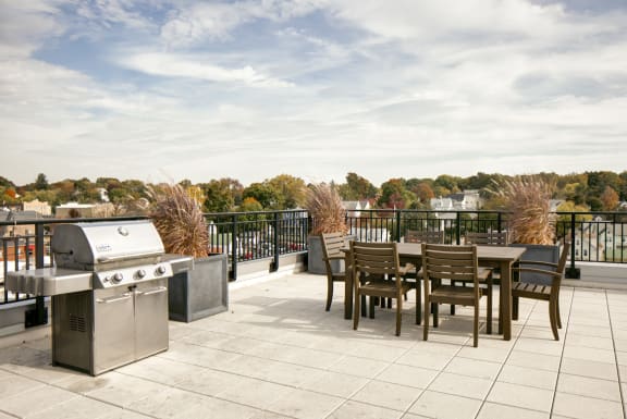 the terrace of a building with a table and chairs and a barbecue grill