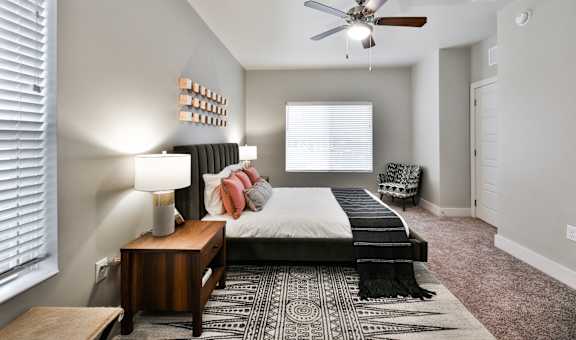 A bedroom with a bed, a nightstand, and a rug.