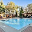 A large outdoor swimming pool surrounded by a brick patio and lounge chairs.